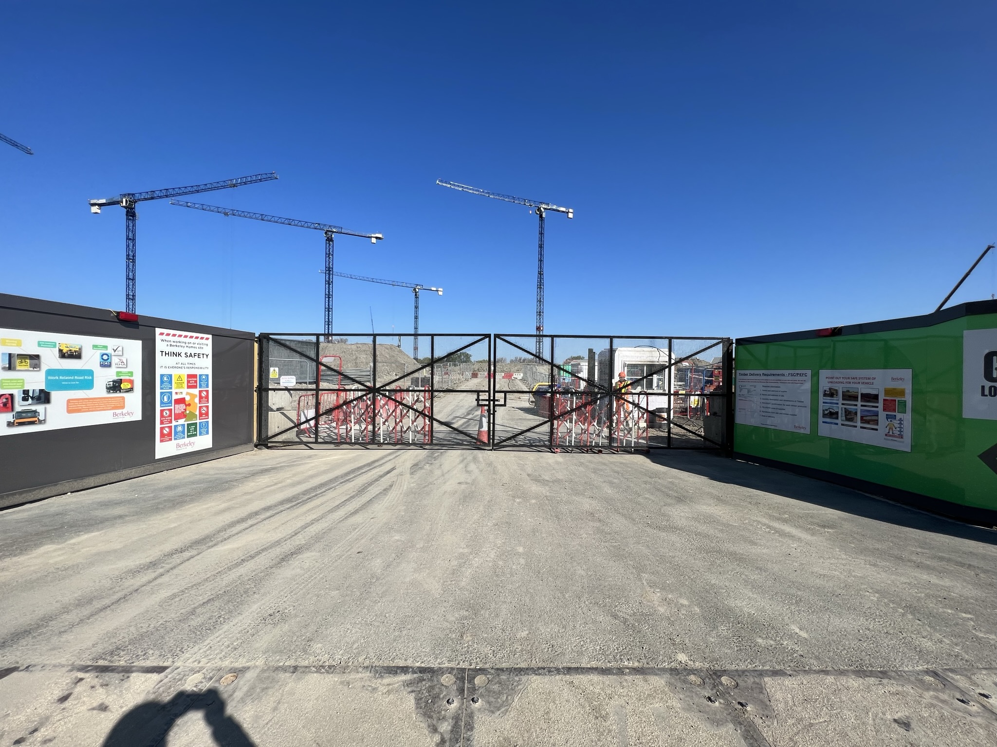 Construction site entrance with large metal gates and branded hoarding